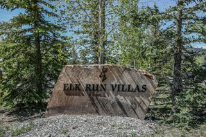 A stone sign with the text "ELK RUN VILLAS" surrounded by trees.