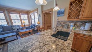 A kitchen with granite countertops, wooden cabinets, and a built-in wine rack. - Elk Run Villas 9574 (Keystone)