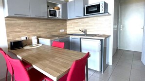 A compact kitchen with a wooden table, red chairs, a microwave, a toaster, and a refrigerator. - Studio cabin in Banyuls-sur-Mer with terrace (Banyuls-sur-Mer)