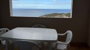 A room with a table and chairs, a window with a view of the sea and a hilly landscape. - Studio cabin in Banyuls-sur-Mer with terrace (Banyuls-sur-Mer)