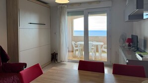A modern room with a sliding glass door leading to an outdoor seating area with white chairs and a table. - Studio cabin in Banyuls-sur-Mer with terrace (Banyuls-sur-Mer)