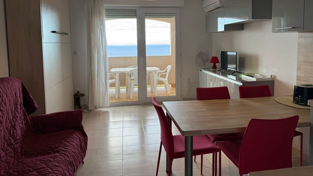 A modern kitchen with a dining area, a TV, and a view of the sea through the sliding glass door. - Studio cabin in Banyuls-sur-Mer with terrace (Banyuls-sur-Mer)