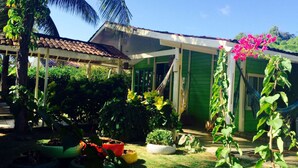 Una casa con puerta verde, un porche cubierto y una hamaca.