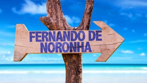 Un letrero de madera con el texto "FERNANDO DE NORONHA" señalando a la derecha.