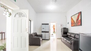 A modern living room with two leather sofas, a white door, and a refrigerator. - Hotel Casa Ariana (Bacalar)