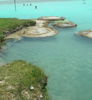 A clear, turquoise pool with rocky formations and grassy edges. - Hotel Casa Ariana (Bacalar)