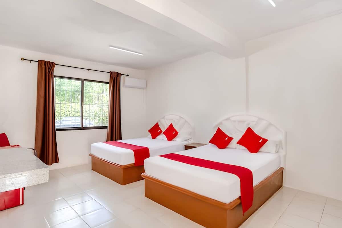 A hotel room with two beds, a desk, and a window with curtains.