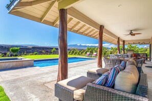 A covered outdoor area with a pool, wicker furniture, and a view of a city and mountains. - Ainamalu 3 Bdrm Home with Pool in Waikoloa Resort! (Waikoloa)