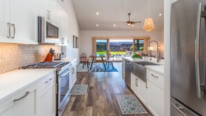 Una cocina moderna con armarios blancos, electrodomésticos de acero inoxidable y un amplio ventanal con vistas al exterior.
