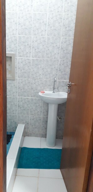A bathroom with a white sink, a blue mat, and a white bathtub.