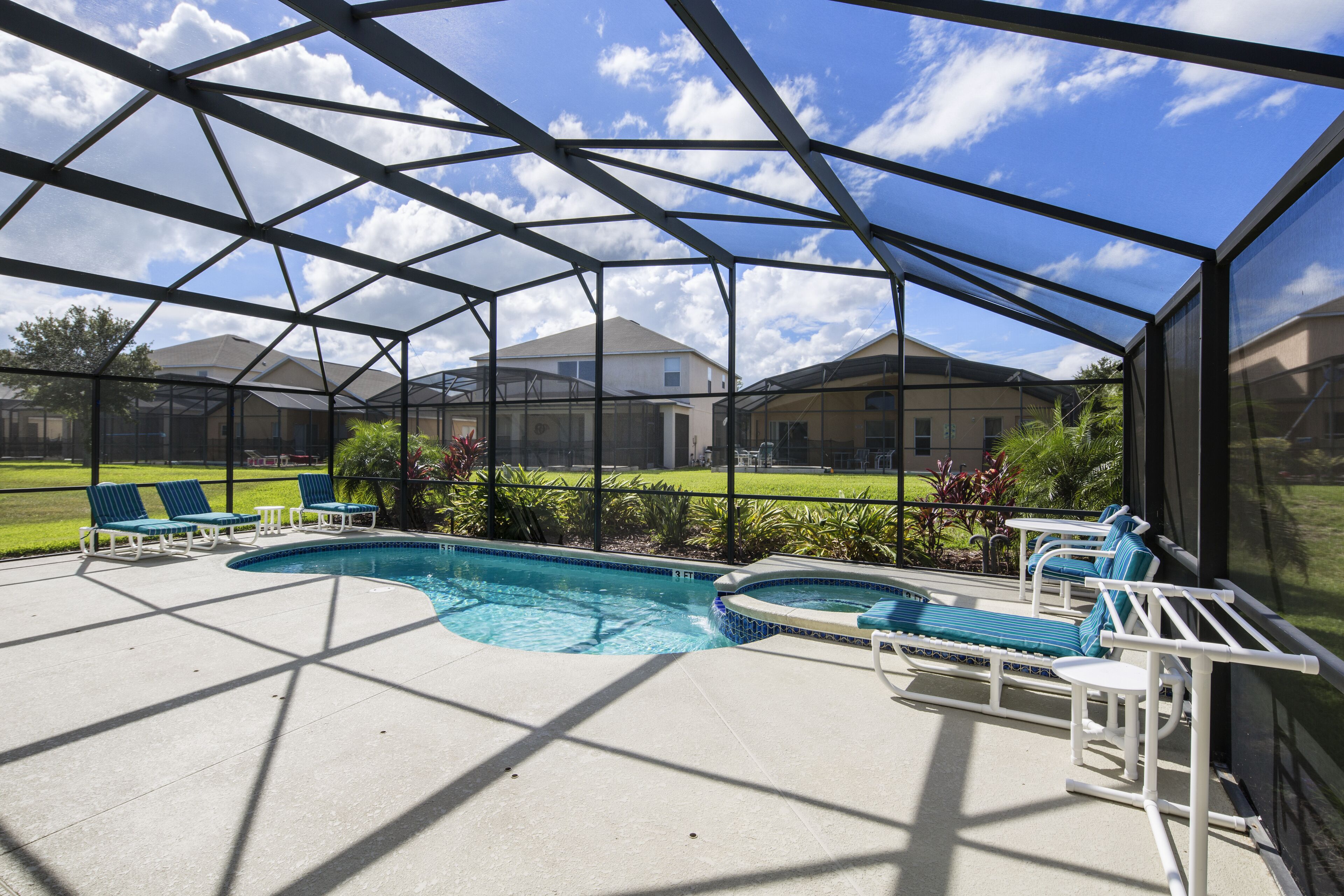 A covered outdoor swimming pool with lounge chairs and a view of residential buildings.