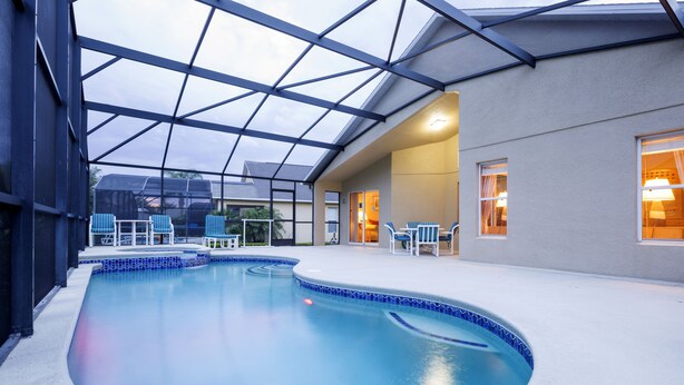Une piscine intérieure dotée d’un toit en verre, d’un bord recouvert de carreaux bleus et de chaises longues.