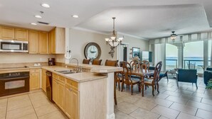 A modern kitchen with wooden cabinets, a built-in microwave, and a large island with a sink. - Sunrise View~Nautical Themed & Family Friendly! (Pensacola Beach)