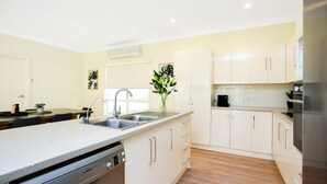 A modern kitchen with a Bosch dishwasher, white cabinets, and a stainless steel refrigerator. - Aldinga Beach Experience (Aldinga Beach)