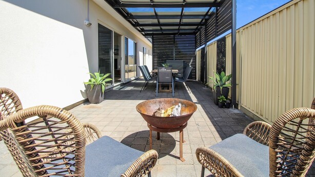 A patio area with wicker furniture, a fire pit, and potted plants. - Aldinga Beach Experience (Aldinga Beach)