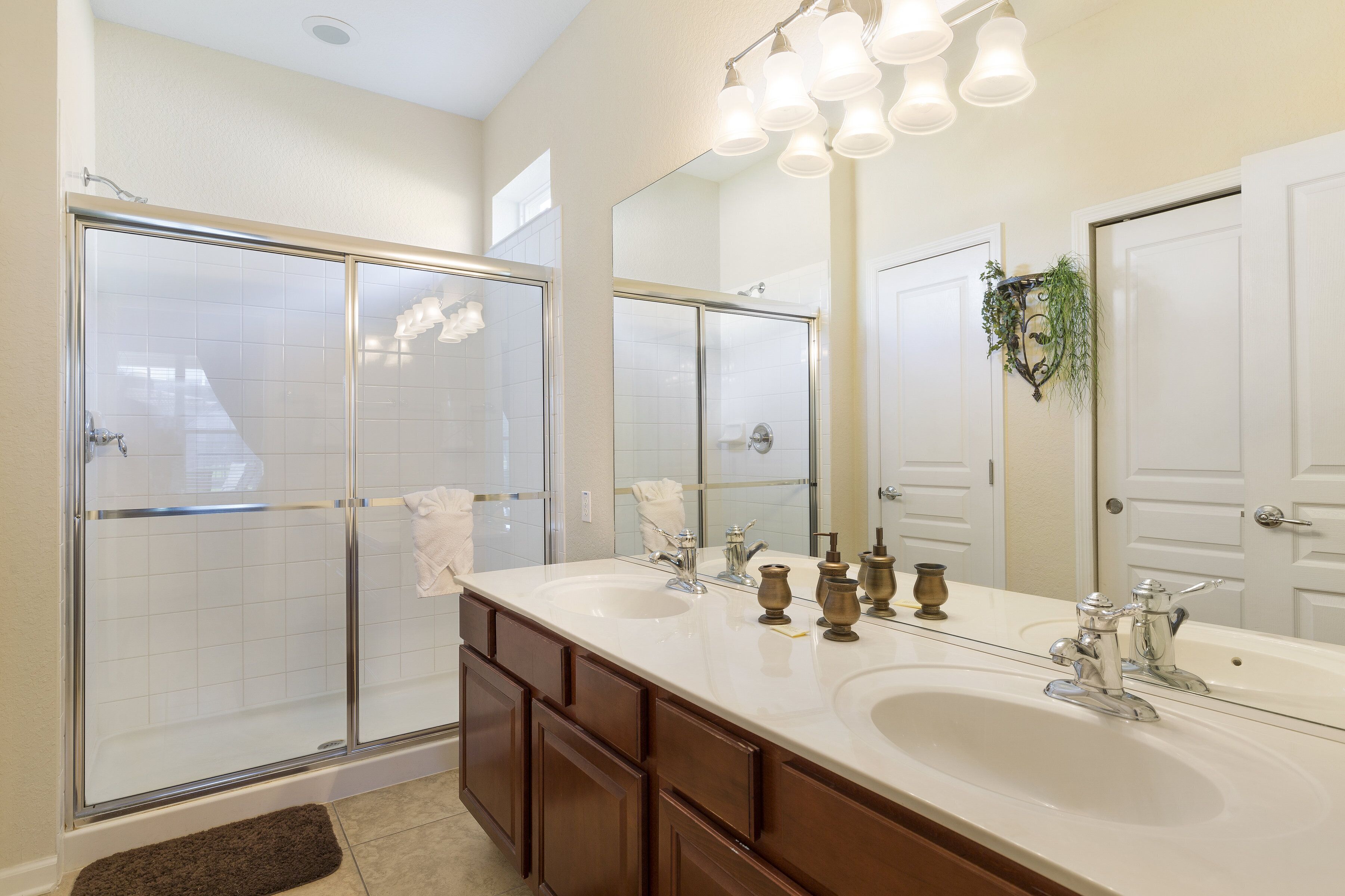 A modern bathroom with a glass shower enclosure, a large vanity with dual sinks, and a mirror above the sink.