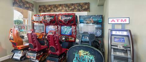 A gaming area with multiple arcade machines, including 'Blazing Angels' and 'Drift' games, and an ATM machine.