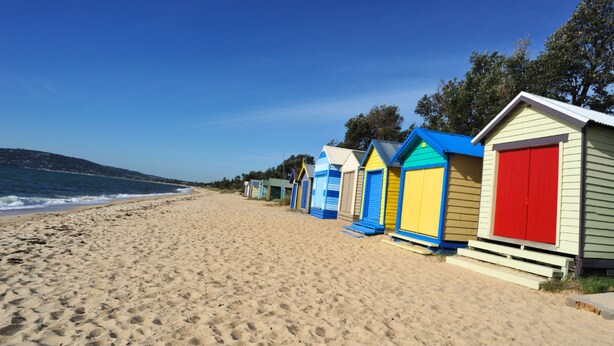 A beach with colorful beach huts and a sandy shoreline.