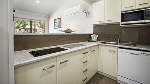 Una cocina moderna con estufa integrada, microondas y lavavajillas. Hay una ventana con vistas al exterior y un cuenco de fruta sobre la encimera.