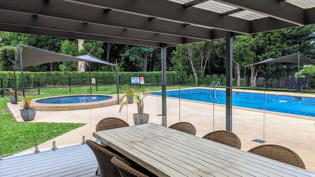 Zona de piscina exterior con terraza cubierta, asientos y un letrero que indica prohibido el acceso.
