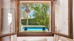 Ein Zimmer mit Blick auf einen Swimmingpool, einem Sessel und einem fenster mit Vorhängen.