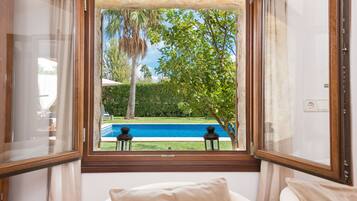Habitación con vista a una piscina, una silla y una ventana con cortinas.