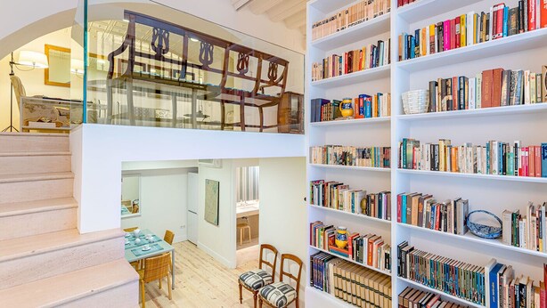 A multi-level interior with a staircase, a dining area, and a large bookshelf filled with books. - Genteel Home Catedral Sevilla (Sevilla)
