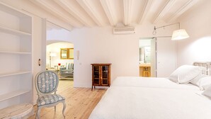 A bedroom with a large bed, a wooden cabinet, a chair, and a desk. - Genteel Home Catedral Sevilla (Sevilla)
