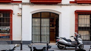A building with a central balcony, a large arched entrance, and a scooter parked in front. - Genteel Home Catedral Sevilla (Sevilla)