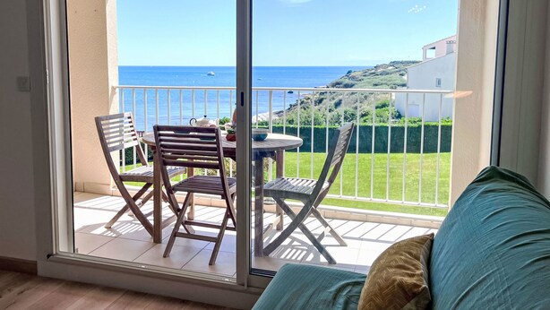 Un balcon avec une table et des chaises, offrant une vue sur la côte.