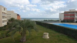 Un quartier résidentiel doté d’une piscine, de palmiers et offrant une vue sur l’océan.
