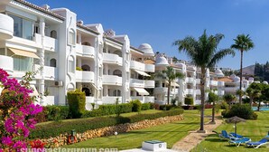 A resort with multiple white buildings, a swimming pool, and palm trees. - P03 La Cortijada - Apartment (Sitio de Calahonda)