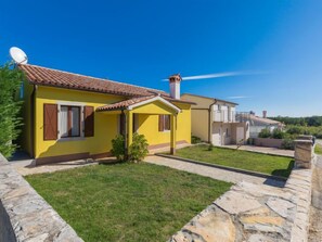 A yellow villa with a tiled roof, a stone pathway, and a small garden. - Vacation home Corina by Interhome (Labin)