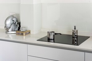 Een keuken met een moderne kookplaat, een koffiezetapparaat en een doos koffiecups.