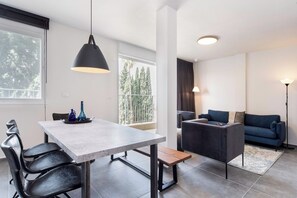 Een moderne woonruimte met een eethoek, een bank en uitzicht op bomen door grote ramen.
