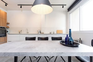 Een moderne keuken met een marmeren aanrecht, zwarte stoelen, een centraal eiland en een hanglamp.