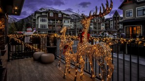 Decorazione con pupazzo di neve e renna su un balcone con montagne sullo sfondo.