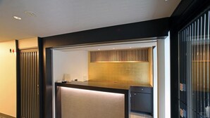 A reception area with a counter, a wall-mounted vent, and a door with a security lock. - Hana Touro Hotel Gion (Kyoto)
