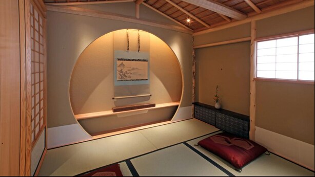 A traditional Japanese room with tatami flooring, a low wooden shelf with a framed picture, and a window with a view. - Hana Touro Hotel Gion (Kyoto)