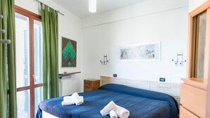Une chambre d’hôtel avec un grand lit, un radiateur, une table de chevet en bois et une fenêtre avec des rideaux verts.