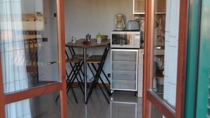 Une cuisine compacte comprenant une table à manger, un luminaire suspendu et un petit réfrigérateur.