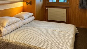 A bedroom with a bed, wooden walls, a window, and a radiator.