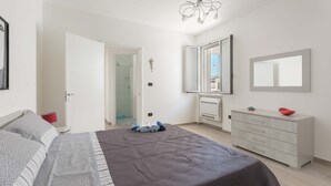 Une chambre à coucher comprenant un lit, une commode, un miroir et une porte donnant sur une salle de bain.