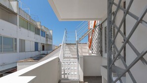 Un couloir étroit avec un escalier en métal menant à une entrée fermée par un portail.