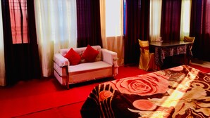 Habitación de hotel con sofá, mesa de comedor y edredón estampado.