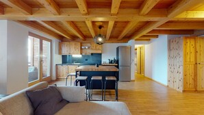 Een moderne keuken met houten kasten, een centraal kookeiland met krukken, en een hangende lamp.