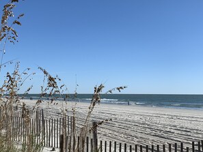 A beach with a wooden fence and waves.