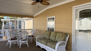 A covered porch with a ceiling fan, white wicker furniture, and a cushioned sofa. - SNOW BIRDS..SPECIAL RATES FOR WINTER TRAVELS - A Fun, Sun N' Surfin' Kinda Place (Murrells Inlet)