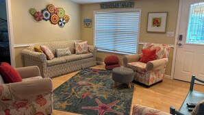 A living room with striped sofas, a starfish rug, and a wall with colorful umbrellas. - SNOW BIRDS..SPECIAL RATES FOR WINTER TRAVELS - A Fun, Sun N' Surfin' Kinda Place (Murrells Inlet)