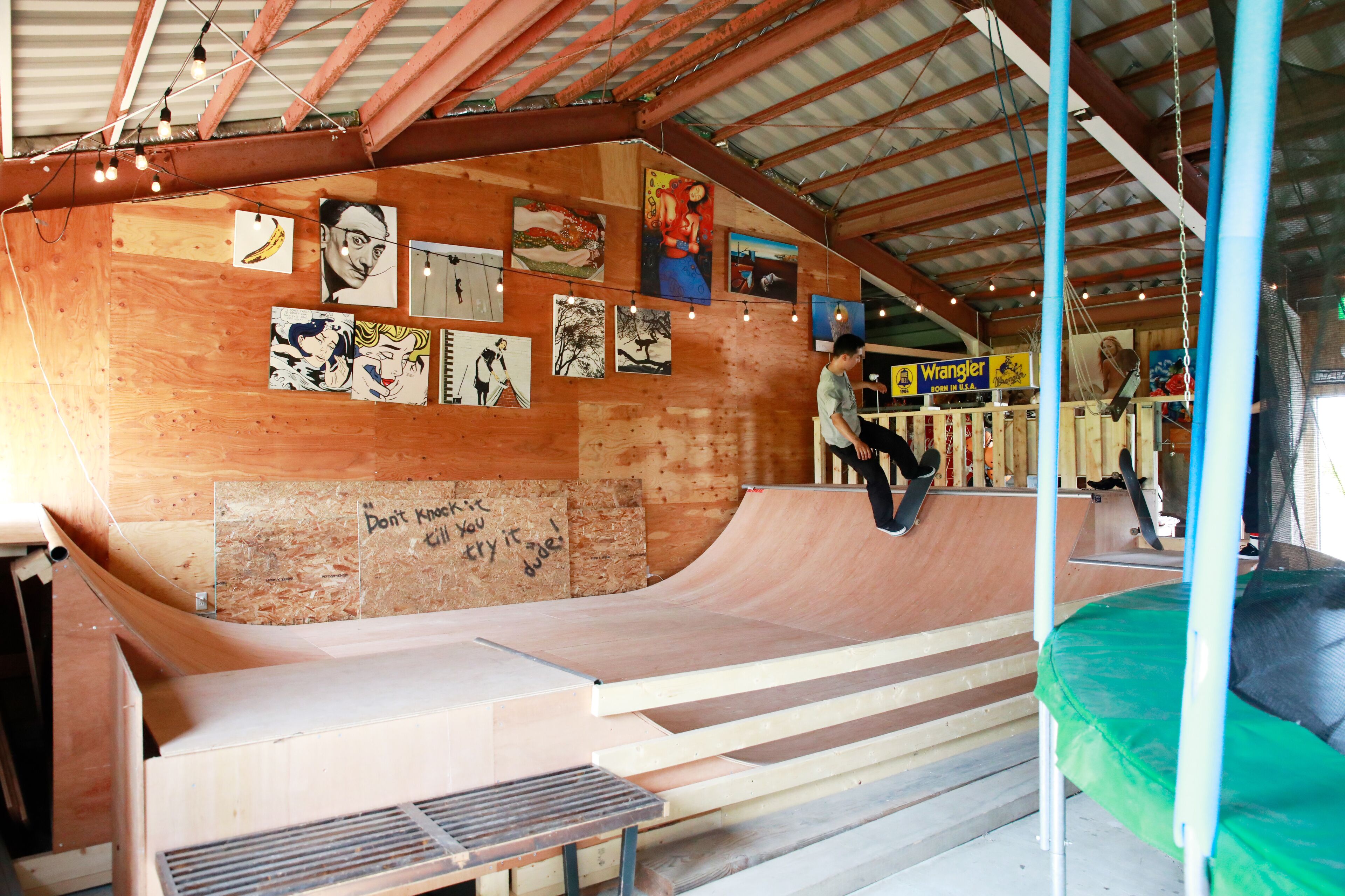 A skate park with wooden ramps and a green trampoline.
